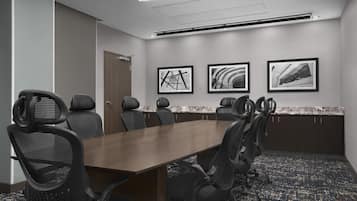 A conference room with a long table, six chairs, and three framed pictures on the wall.