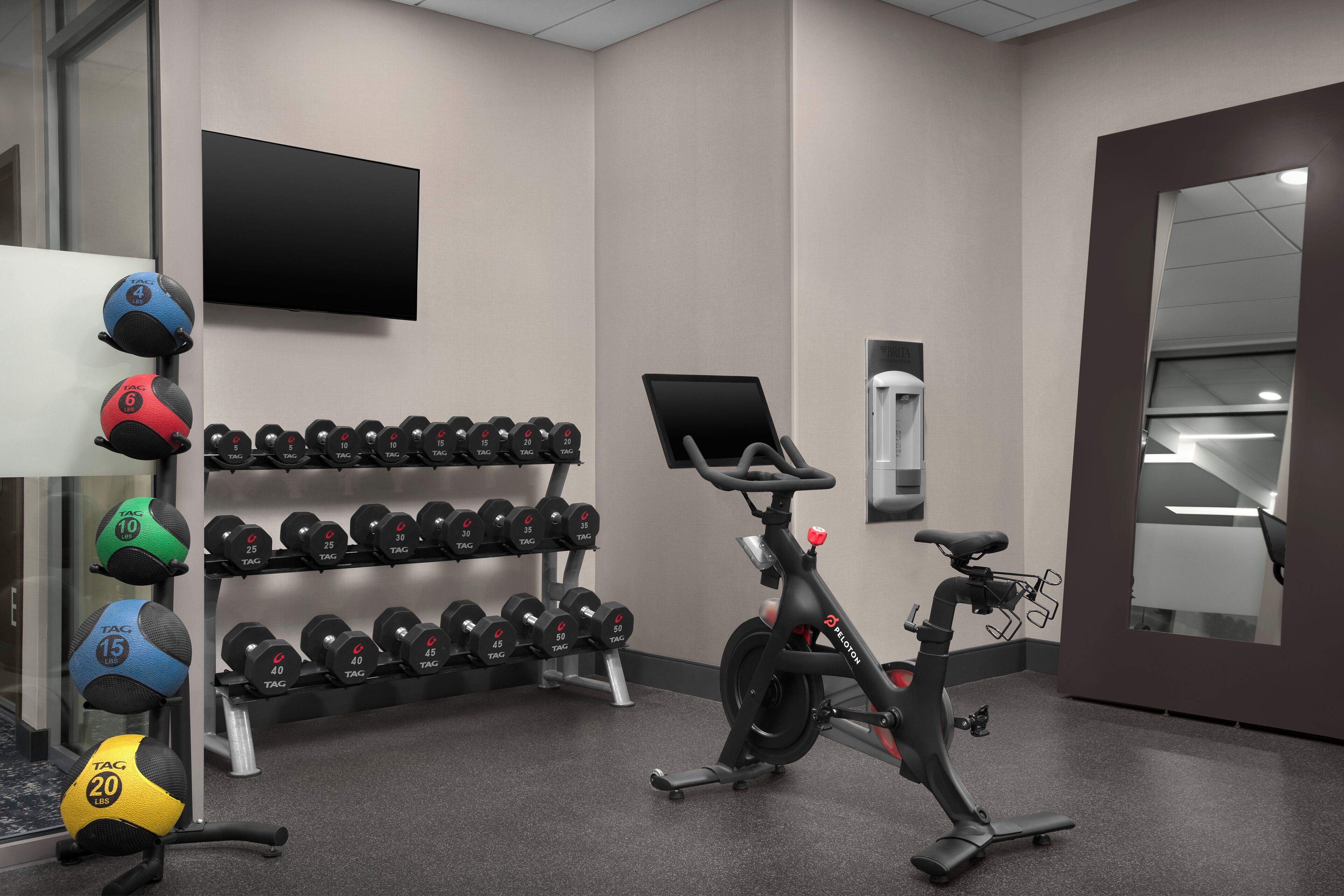 A gym with exercise equipment, a TV, and a mirror.