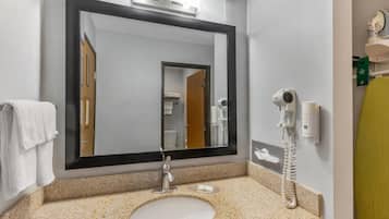 Un bagno con uno specchio grande, un lavandino, un asciugacapelli e un telefono.