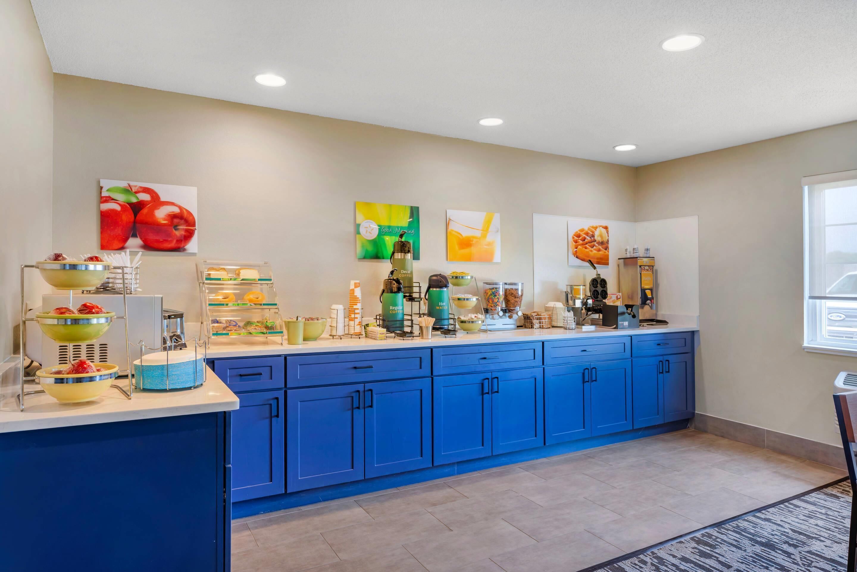 A kitchen area with a blue countertop, various kitchen appliances, and a window with a view.