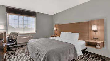 Una habitación de hotel con una cama grande, un escritorio con silla, un ventanal con vistas y dos lámparas de noche.