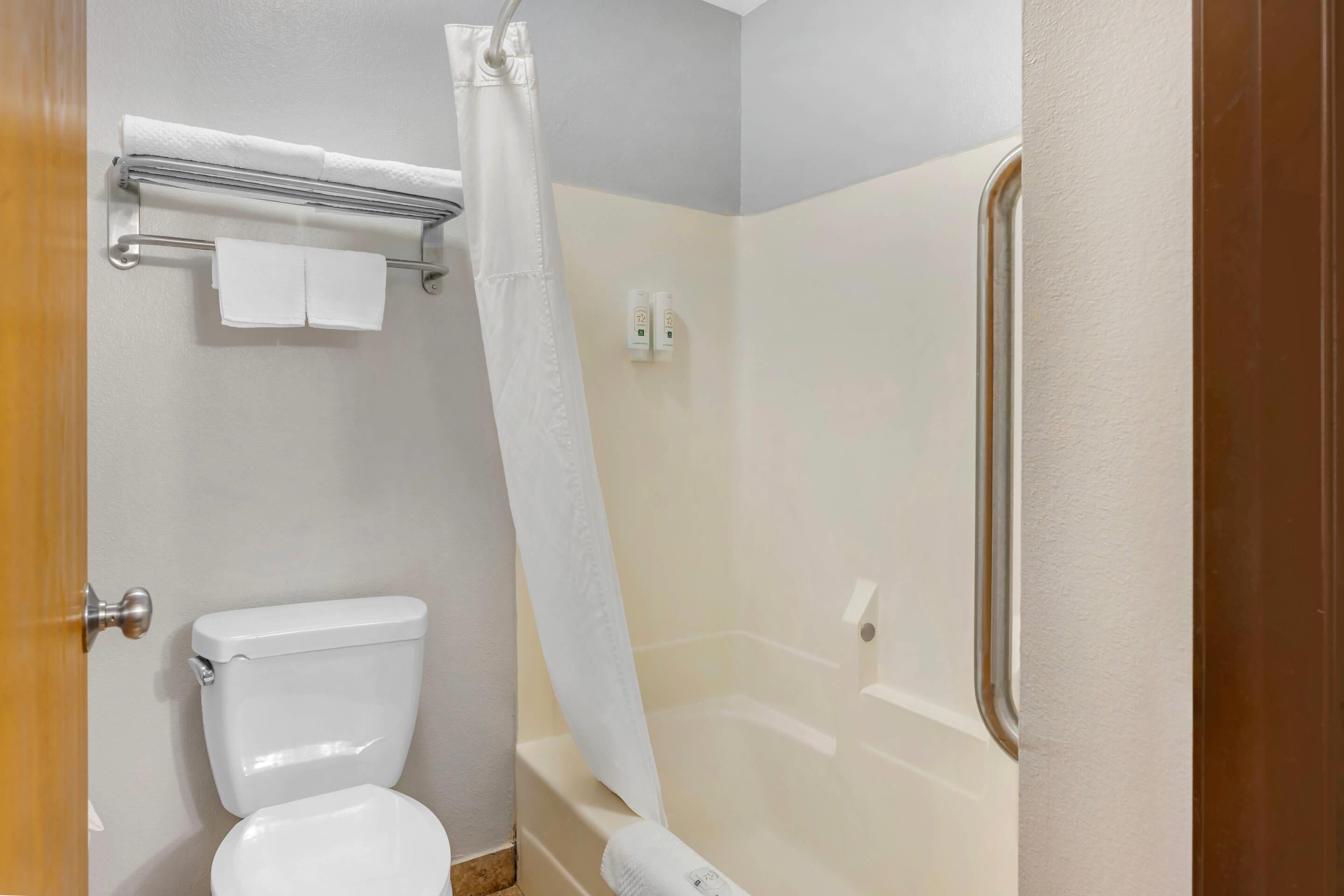 A bathroom with a toilet, a shower curtain, and a towel rack.