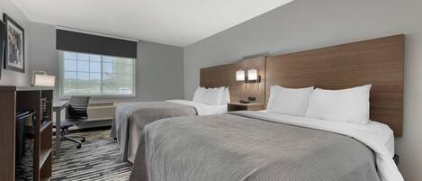 Une chambre d’hôtel avec deux lits, un bureau, une chaise et une grande fenêtre.