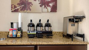A kitchenette with a coffee station featuring a Bunn coffee maker, a water dispenser, and a hot coffee dispenser. - Red Roof Inn Jacksonville - Cruise Port (Jacksonville)