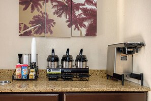 Un angolo cottura con un angolo caffè dotato di una macchina da caffè Bunn, un dispenser di acqua e un erogatore di caffè caldo.