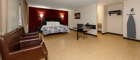 A hotel room with a bed, a desk, a chair, and a wardrobe.