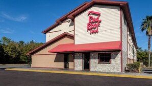 A Red Roof Inn with a red awning, beige exterior walls, and a stone accent wall. - Red Roof Inn Jacksonville - Cruise Port (Jacksonville)