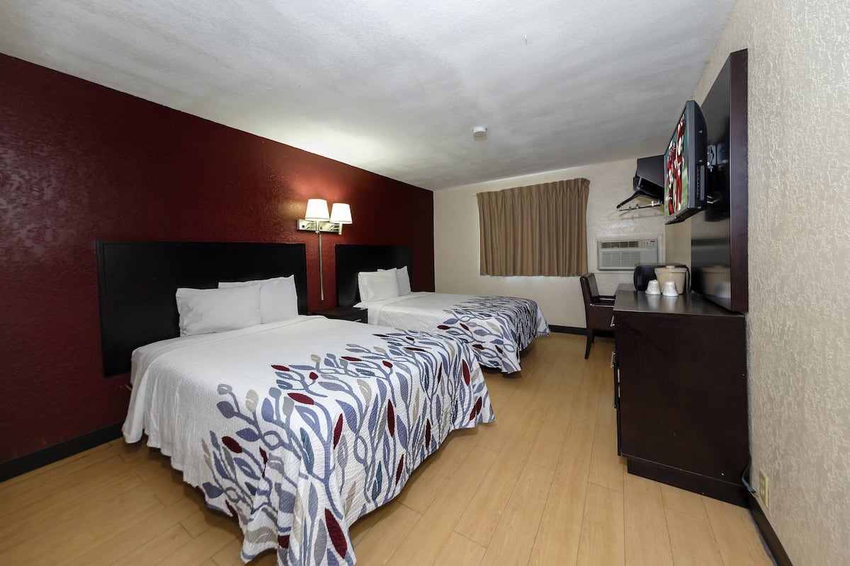 A hotel room with two beds, a desk, a television, and a minibar.