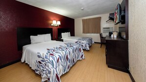 A hotel room with two beds, a desk, a television, and a ceiling light. - Red Roof Inn Jacksonville - Cruise Port (Jacksonville)