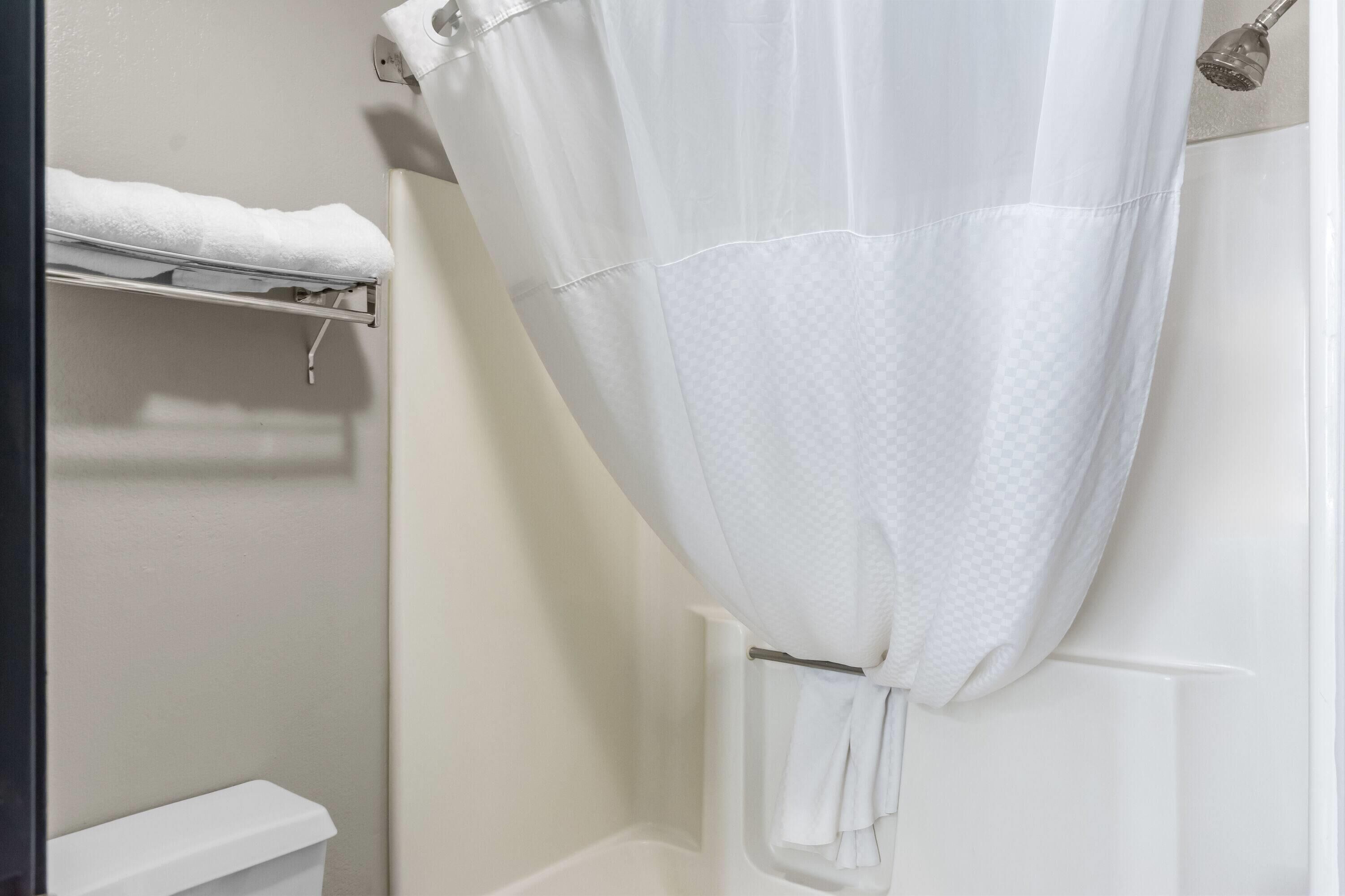 A bathroom with a shower curtain, a towel rack with a towel, and a toilet.
