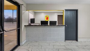 A reception desk with a Super B sign, two monitors, and a tiled wall. - Super 8 by Wyndham Evansville East (Evansville)