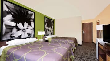 A hotel room with two beds, a television, a desk with a lamp, and a large flower painting on the wall.
