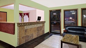A reception area with a tiled counter, a black leather sofa, and a tiled floor.