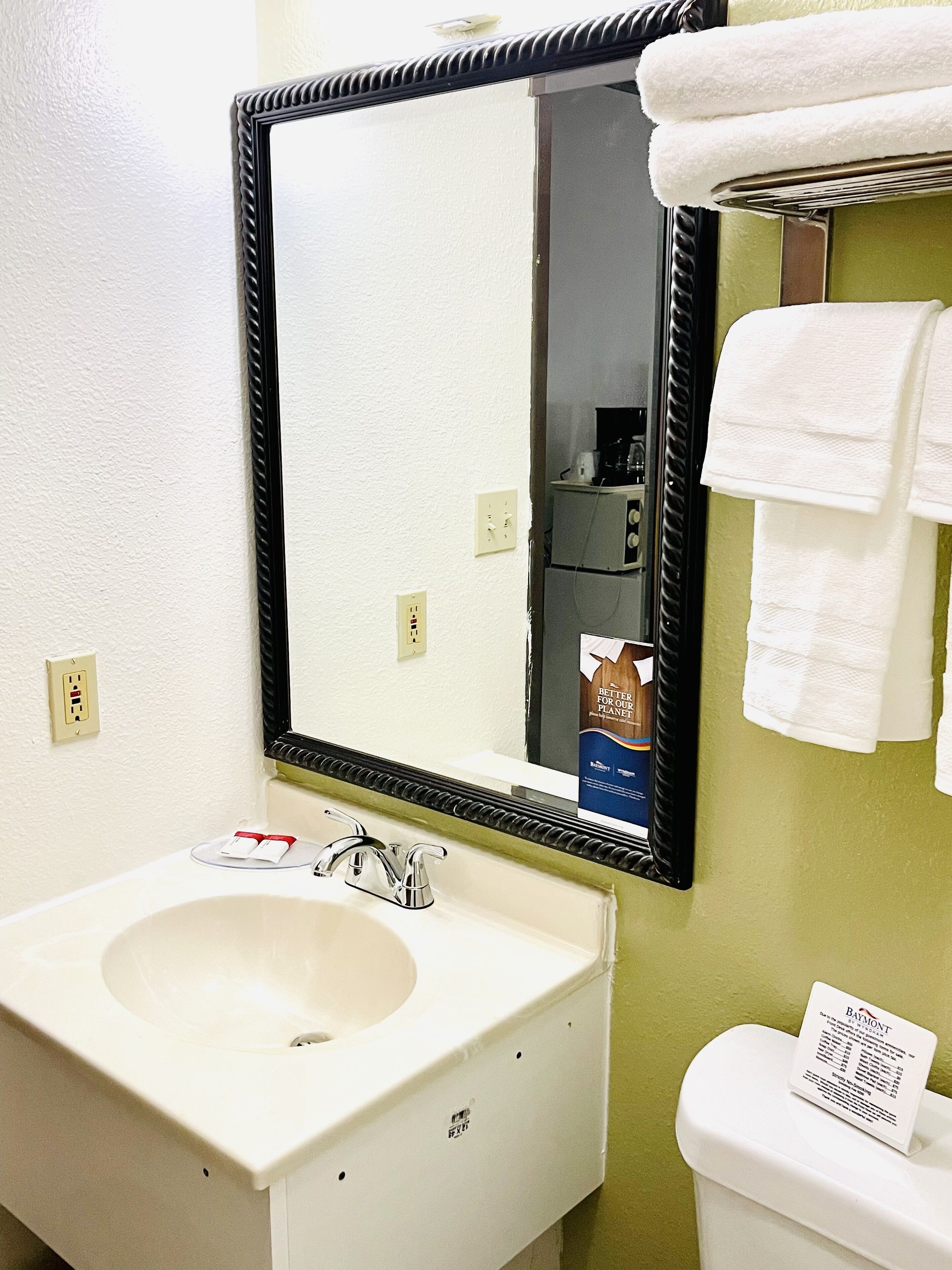 Een badkamer met een witte wastafel, een spiegel en een toilet.