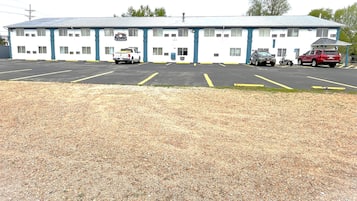 A motel with a large parking lot, a single-story building, and a small attached garage.
