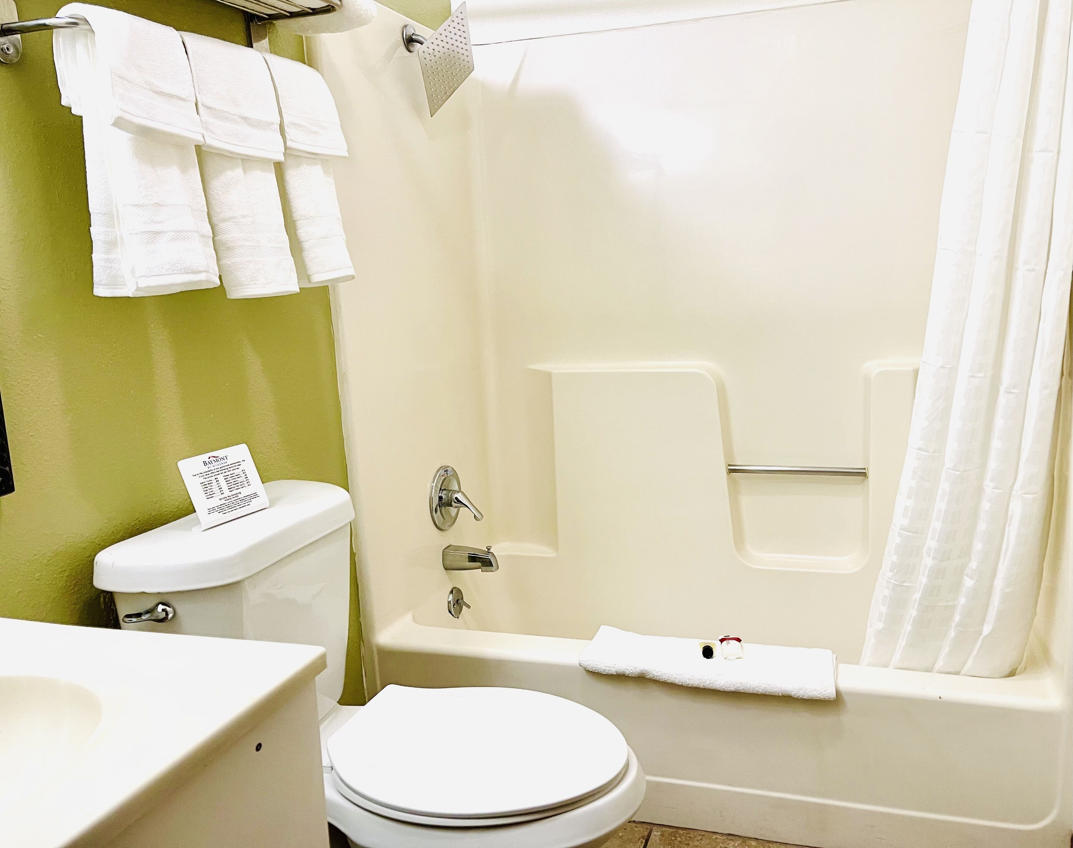 A bathroom with a toilet, sink, and bathtub. There are towels hanging on the wall and a shower curtain.