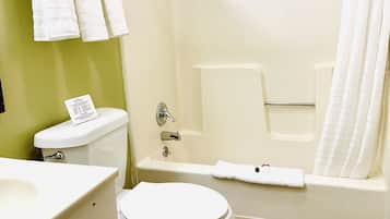 A bathroom with a toilet, sink, and bathtub. There are towels hanging on the wall and a shower curtain.