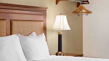 Une chambre d’hôtel avec une tête de lit en bois, une lampe de chevet et un porte-manteau en bois fixé au mur.