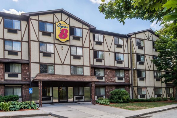 A multi-story hotel with a prominent 'Super 8' sign, a covered entrance, and a brick facade. - Super 8 by Wyndham Groton (Groton)