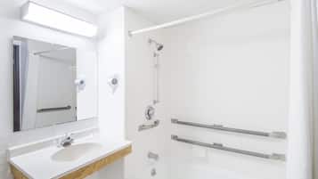 Un bagno con lavandino, specchio e doccia bianchi.
