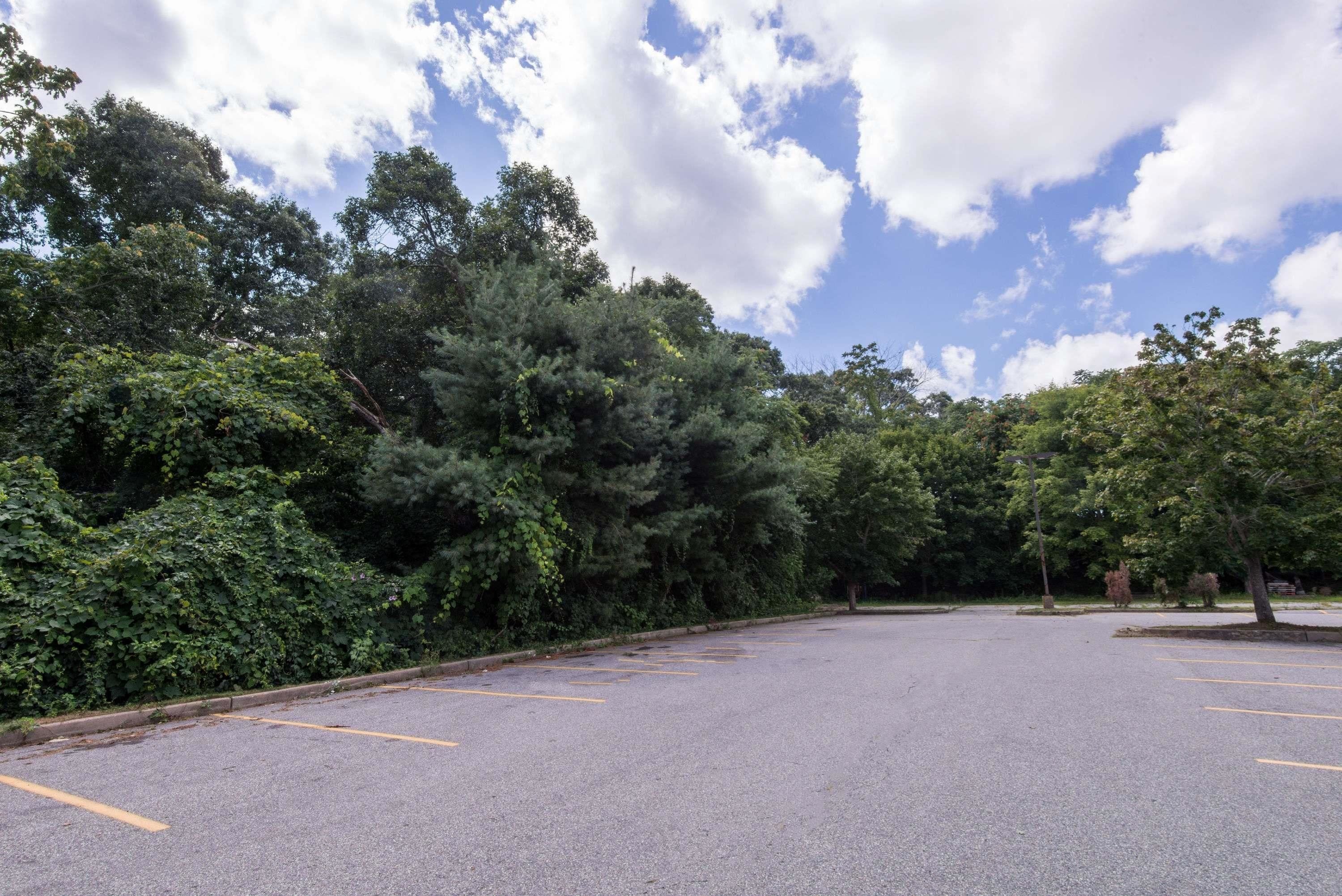 A parking lot with trees and a clear sky.