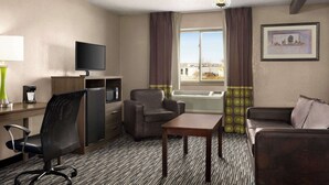 A hotel room with a desk, two armchairs, a sofa, a TV, and a window with curtains. - Super 8 by Wyndham Joliet I-55 N/Chicago (Joliet)