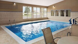 An indoor swimming pool with clear glass walls, a tiled floor, and a view of the outdoors. - Super 8 by Wyndham Joliet I-55 N/Chicago (Joliet)