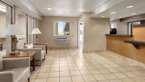 A hotel lobby with a reception desk, seating area, and large windows. - Super 8 by Wyndham Joliet I-55 N/Chicago (Joliet)