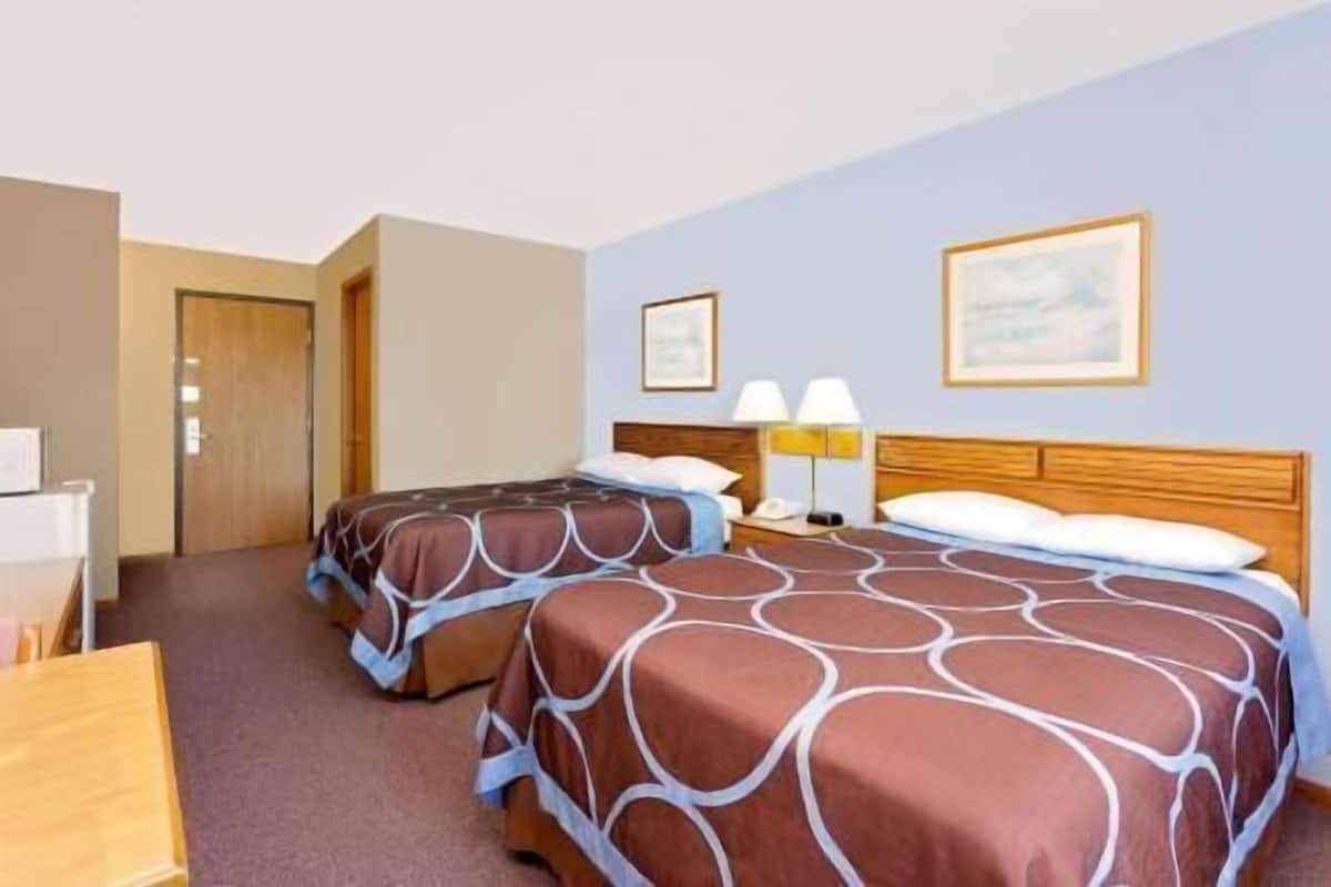 Une chambre d’hôtel avec deux lits, un bureau, une chaise et deux lampes.