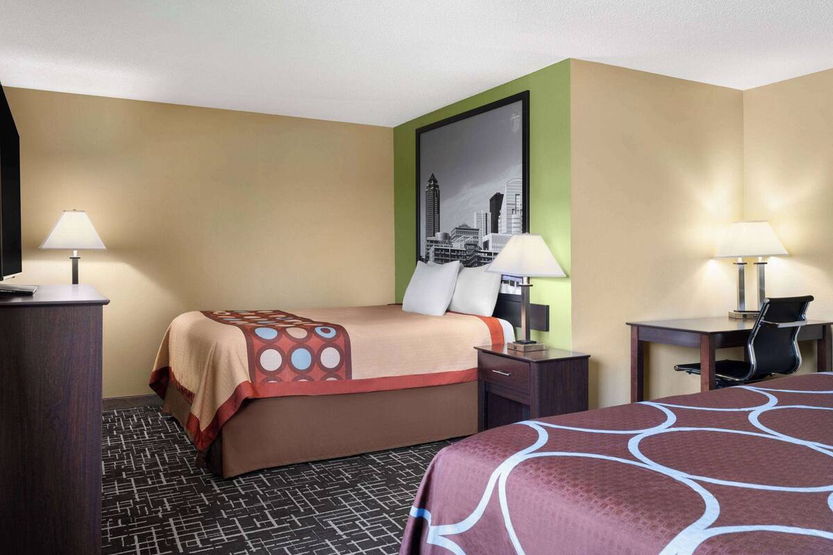 Une chambre d’hôtel équipée d’un lit, d’un bureau, d’une chaise et de deux lampes.