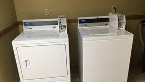 Two white front-loading washing machines with digital displays, placed side by side on a tiled floor.