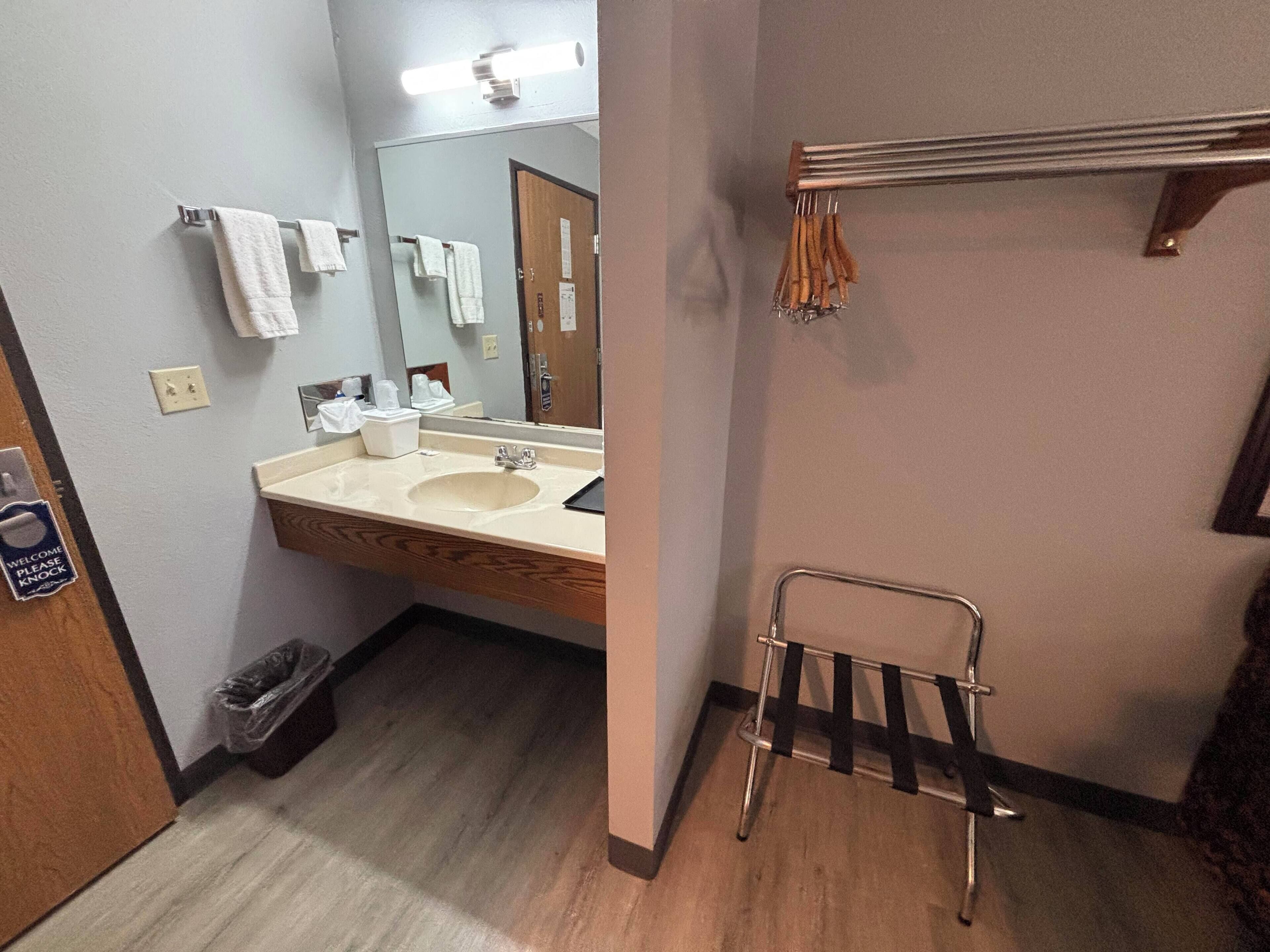 Un baño con lavamanos, espejo y perchero para toallas.