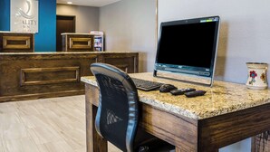 A hotel reception desk with a laptop, a computer mouse, and a keyboard. There is a Coca-Cola refrigerator and a sign for the Quality Inn. - Quality Inn Great Bend (Great Bend)