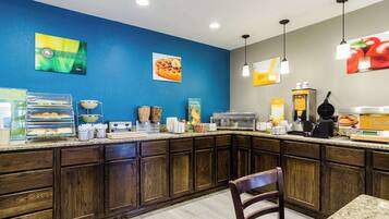 A breakfast bar with a blue wall, wooden cabinets, and various breakfast items.