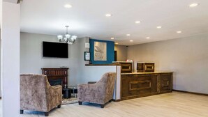 A spacious living area with two plush armchairs, a wooden entertainment center, a flat-screen TV, and a chandelier. - Quality Inn Great Bend (Great Bend)