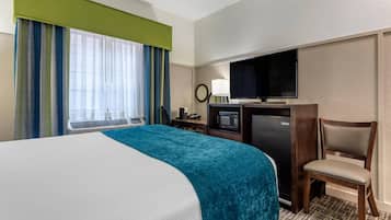 Une chambre d’hôtel équipée d’un lit, d’une télévision, d’un bureau avec un micro-ondes et d’une chaise.