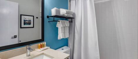 Un baño con lavamanos, espejo y cortina de ducha.