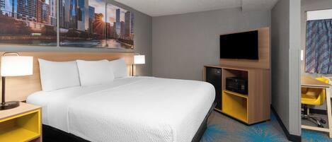 A hotel room with a large bed, a flat-screen TV, a desk with a chair, and a cityscape mural on the wall.