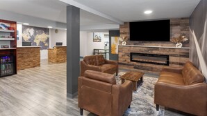 A modern living room with leather sofas, a flat-screen TV, a fireplace, and a reception desk. - Days Inn by Wyndham Waukegan (Waukegan)