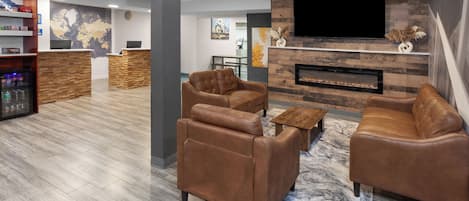 A modern living room with leather sofas, a flat-screen TV, a fireplace, and a reception desk.
