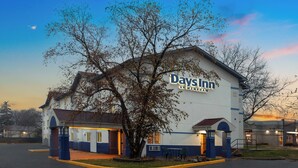A Days Inn building with a large tree in front, a parking lot, and a clear sky. - Days Inn by Wyndham Waukegan (Waukegan)