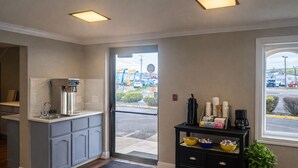 A kitchen with a coffee station, a door leading outside, and a small table with dishes. - Super 8 by Wyndham Lewiston (Lewiston)