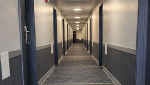 A long, narrow hotel corridor with carpeted floors, doors on both sides, and a ceiling light. - Super 8 by Wyndham Lewiston (Lewiston)