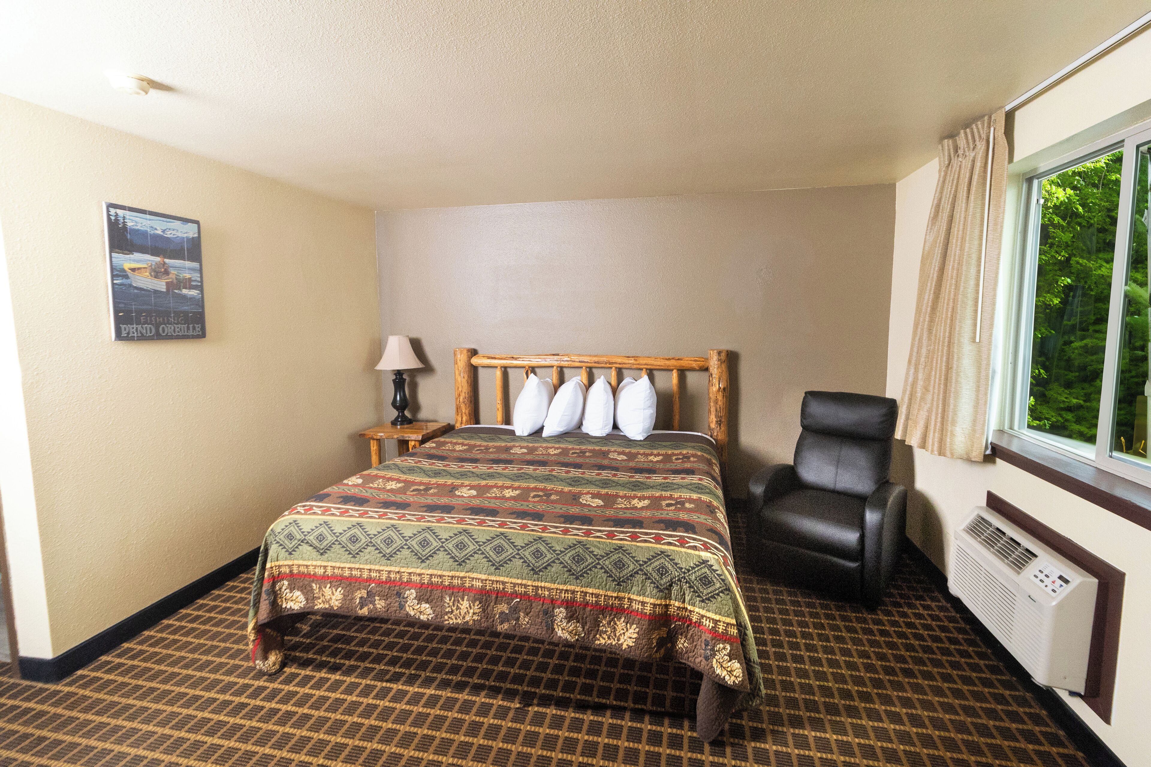 Ein Hotelzimmer mit einem Bett, einem Sessel, einem Nachttisch, einer Lampe und einem Fenster mit Vorhängen.