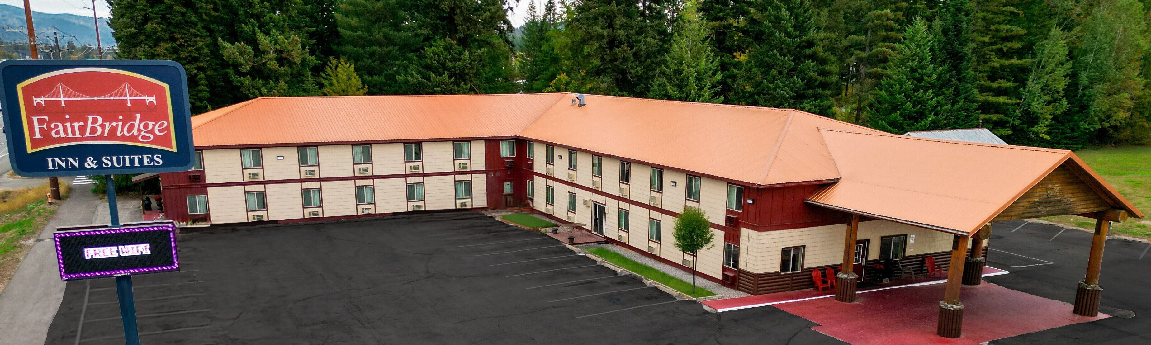 A FairBridge Inn & Suites with a large parking lot and a covered outdoor seating area.