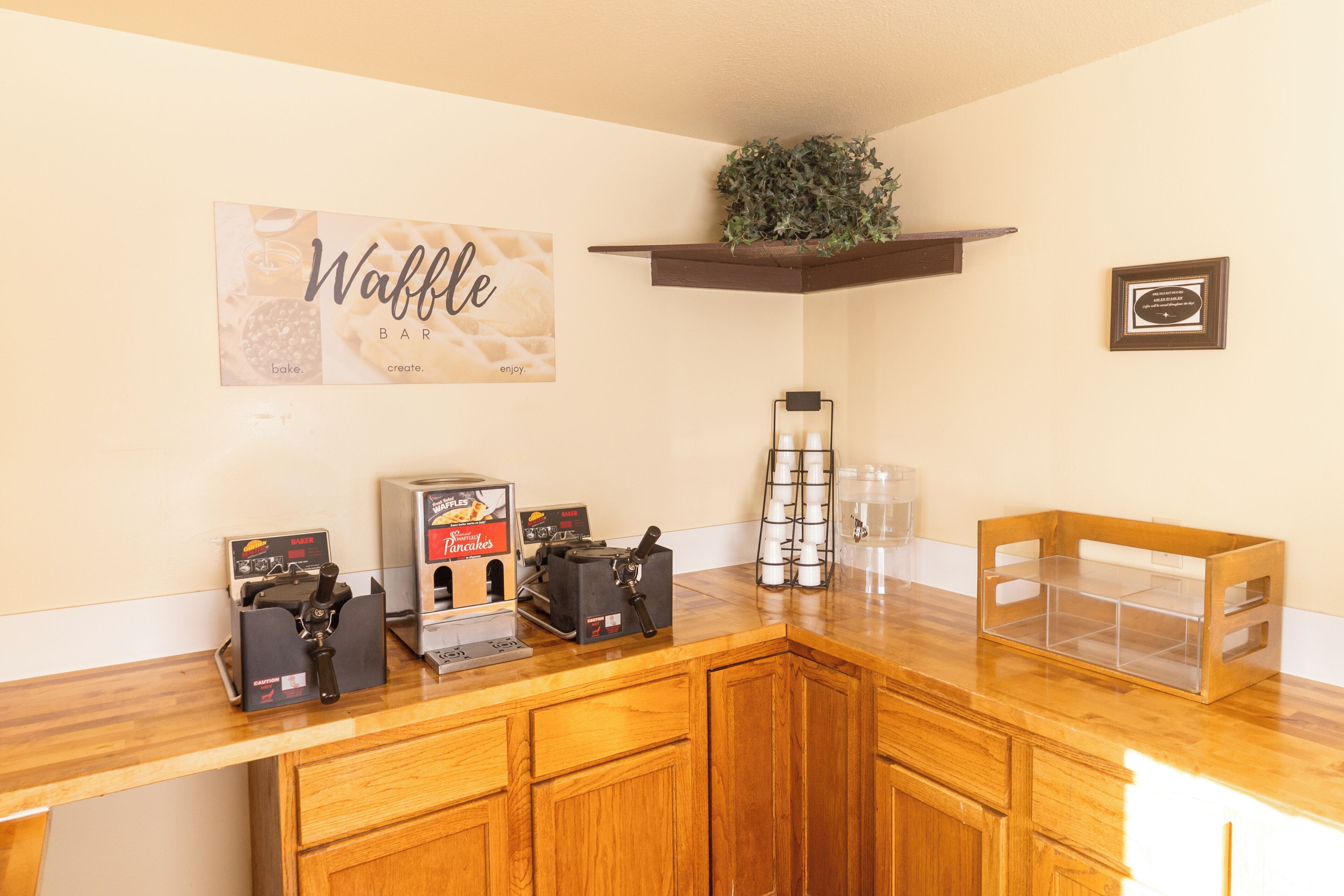 A kitchen counter with waffle makers, a coffee machine, and a waffle sign.