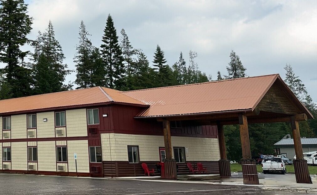 Un bâtiment à deux étages, doté d’un toit rouge et de murs de couleur beige, et comprenant un espace d’entrée abrité avec des bancs.