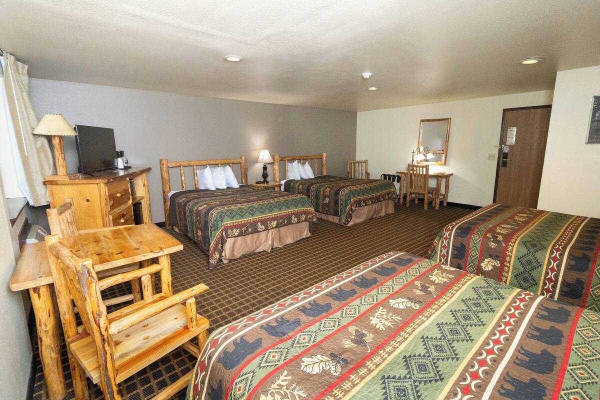 A hotel room with two beds, a wooden desk, a chair, a TV, and a mirror.
