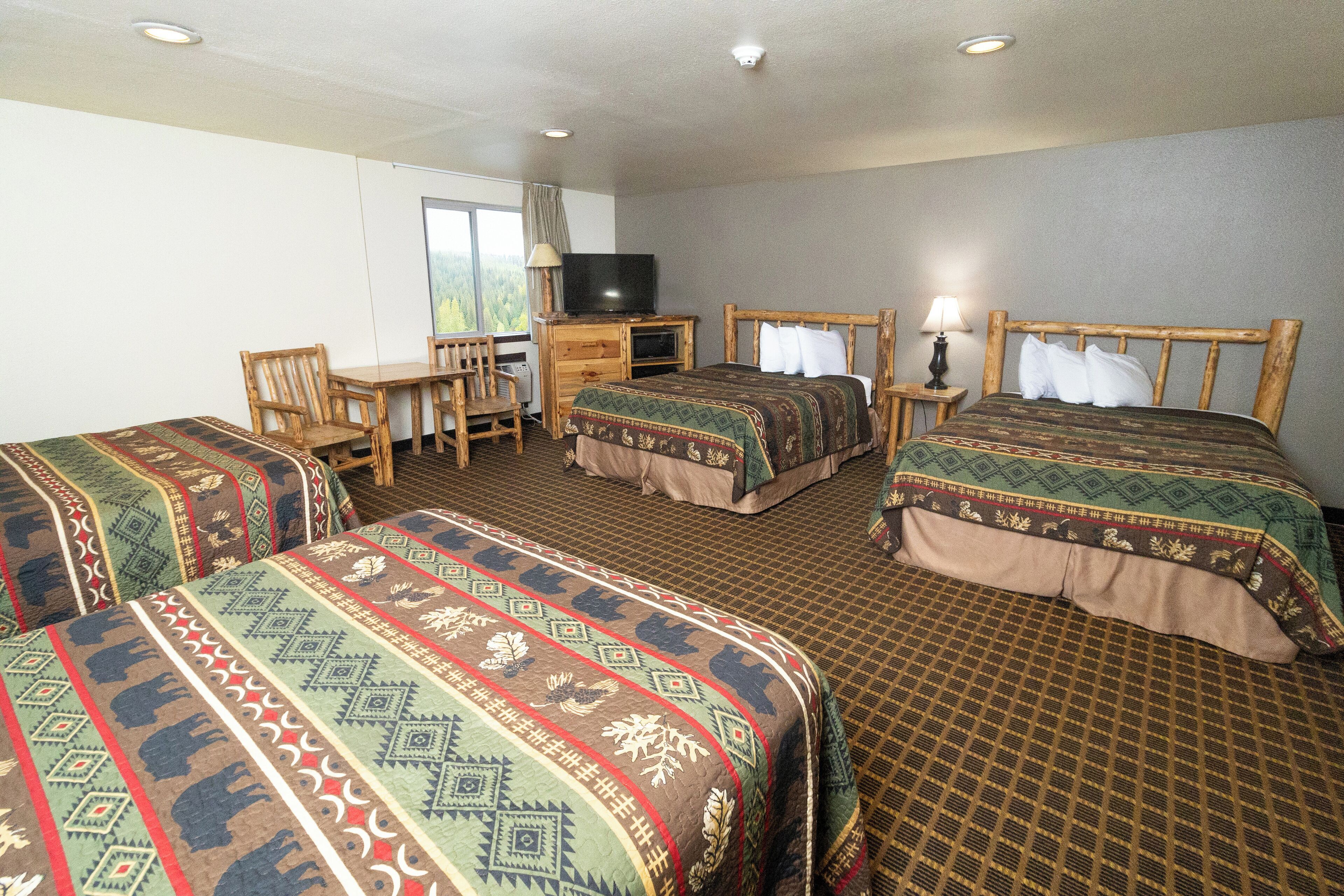 A hotel room with two beds, a TV, a desk, and a chair.