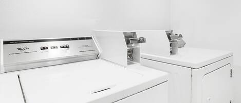 Lavadora comercial resistente de color blanco, con un panel de control que muestra distintas opciones.